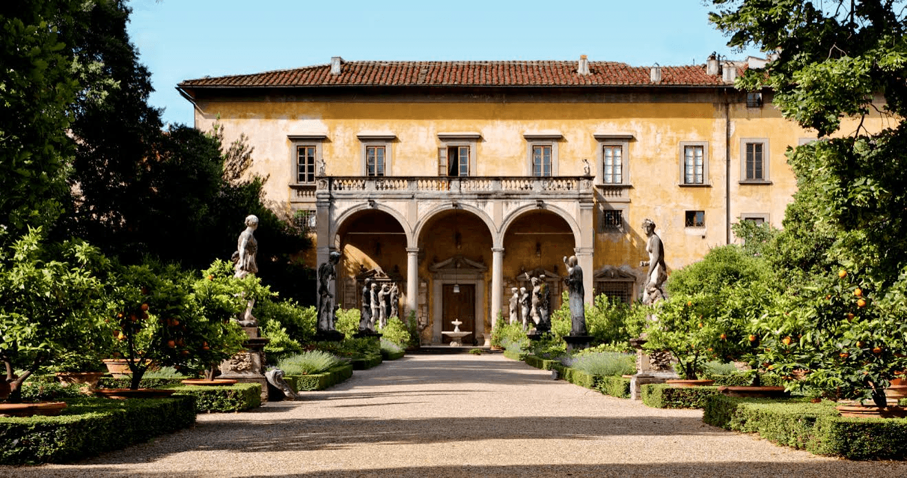 Yellow palazzo facade with a three-arched loggia, garden statues and potted citrus trees